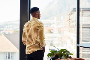 Hombre mirando por la ventana reflexionando sobre su salud
